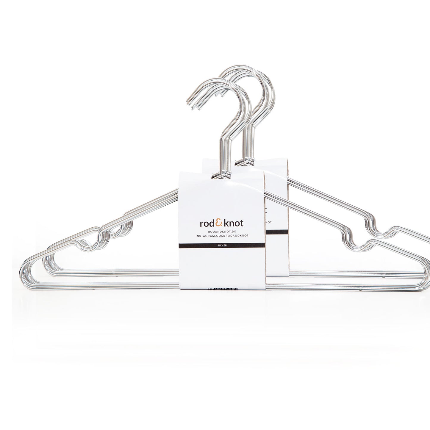 Ein Satz Kleiderbügel aus stabilem Metall, gekennzeichnet mit einem weißen Etikett „Rod & Knot“. Diese designorientierten Kleiderbügel sind auf einem schlichten weißen Hintergrund positioniert und bieten platzsparende Aufbewahrung.