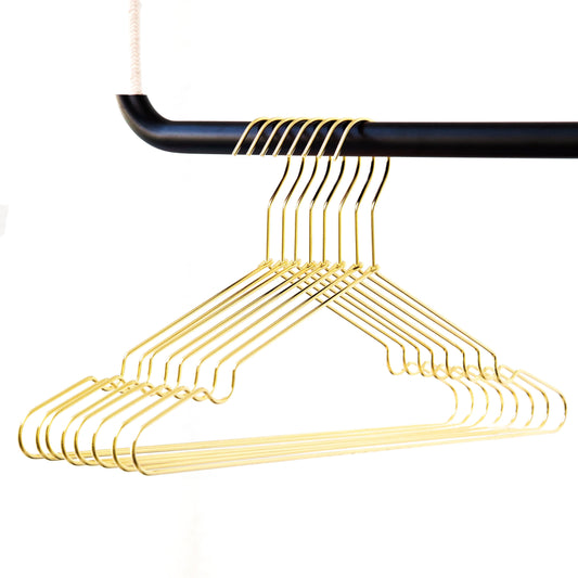 Ein Satz goldfarbener Kleiderbügel aus stabilem Metall – 8 Stück von Rod & Knot, die an einer schwarzen Stange vor einem weißen Hintergrund hängen. Die Bügel sind ordentlich angeordnet und zeigen ihr schlankes und minimalistisches Design.